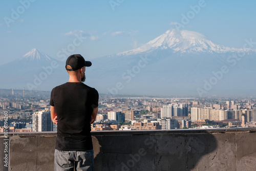 A tourist (infocus) looking at Yerevan and Mount Ararat (out of focus) from Cascade Complex view point on sunny summer day. Armenia. photo