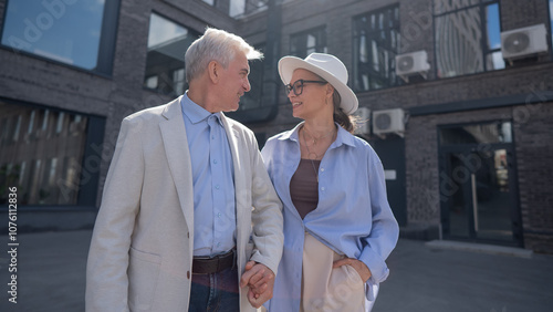 An elderly couple in love walks through the city.  photo