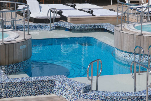 Sonnenliegen auf Luxus Kreuzfahrtschiff - Sun loungers and deck chairs on outdoor promenade Swimmingpool pool deck of  luxury cruiseship or cruise ship liner photo