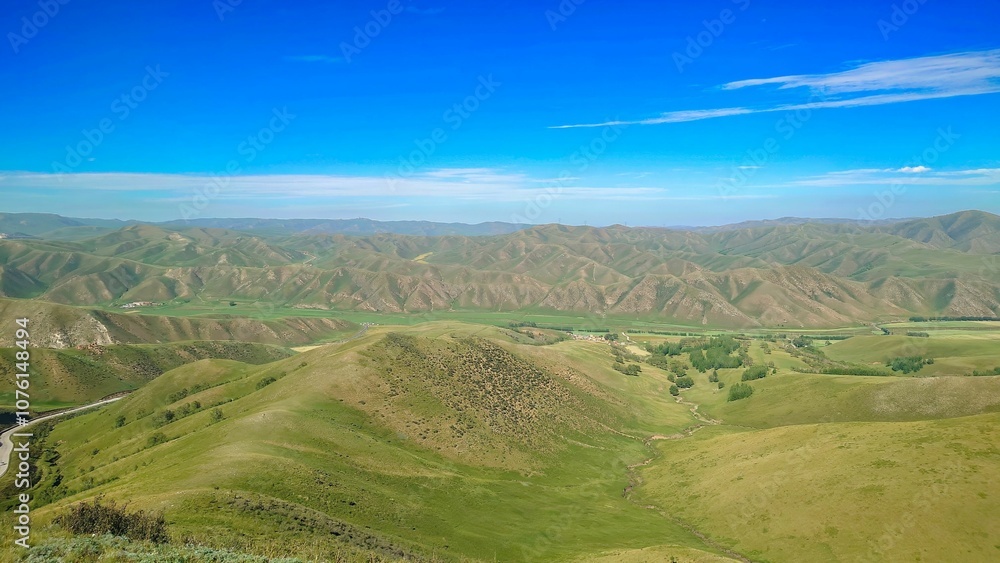 Fototapeta premium Expansive view of rolling green hills under a vibrant blue sky.
