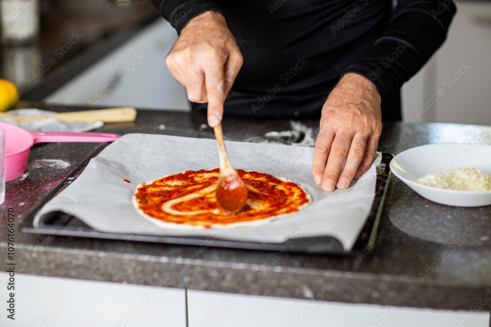 Person adding tomato sauce to pizza heart shaped Person adding tomato sauce to pizza heart shaped