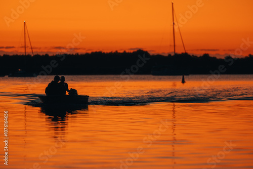 Silhouette image of two people in small dinghy on the Clarence River at sunset photo