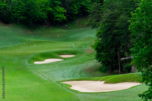 Golf course fairway, sand traps with grass and trees.