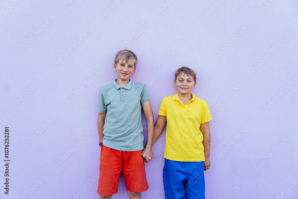 Fototapeta premium Two young boys standing against a colorful purple wall