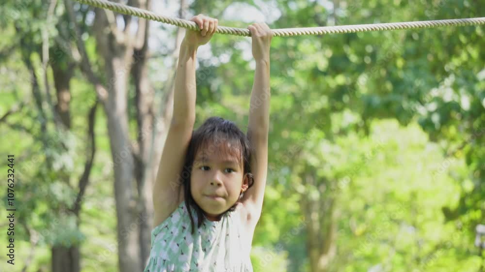 Cute sisters are having fun hanging from ropes in an outdoor park. Children playing in the playground during summer vacation. Cute sisters are having fun hanging from ropes in an outdoor park. Children playing in the playground during summer vacation.