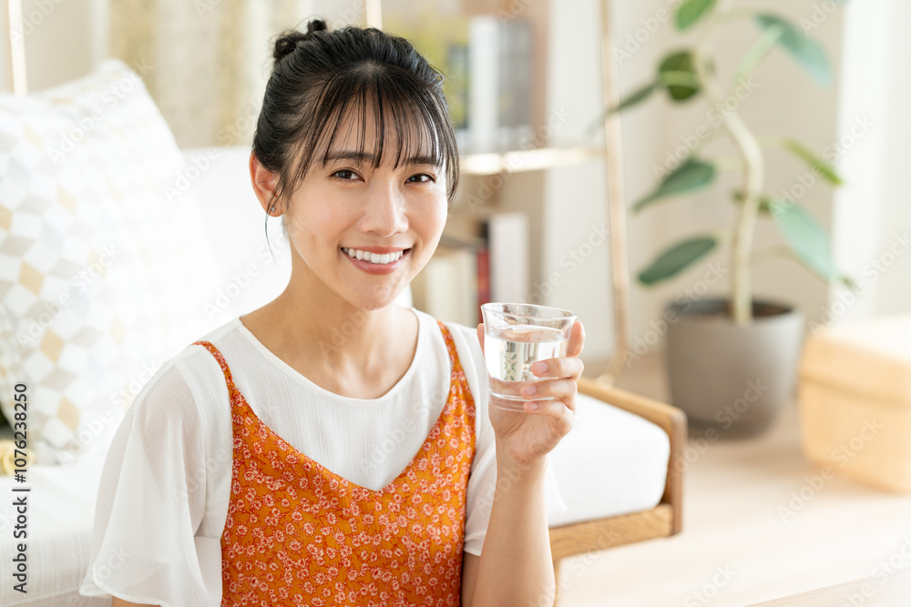 リビングで水を飲む若い女性
