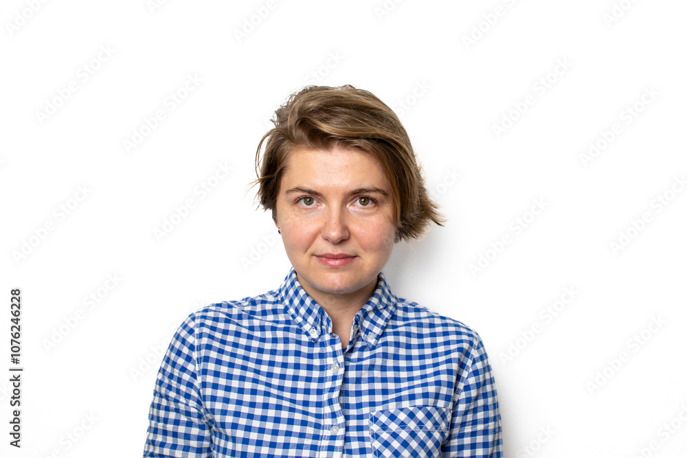 Fototapeta premium A Caucasian woman in a blue checkered shirt poses confidently against a white background, symbolizing self-awareness and empowerment