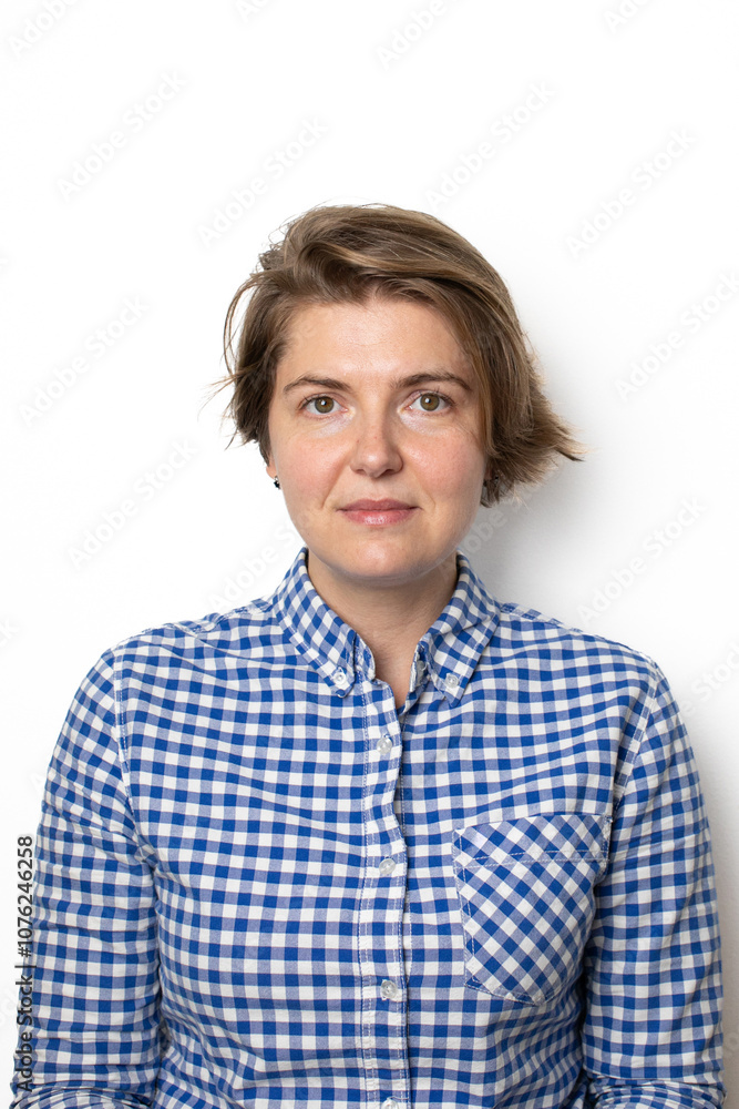 A Caucasian woman in a blue plaid shirt smiles subtly against a plain background, symbolizing confidence and casual fashion A Caucasian woman in a blue plaid shirt smiles subtly against a plain background, symbolizing confidence and casual fashion