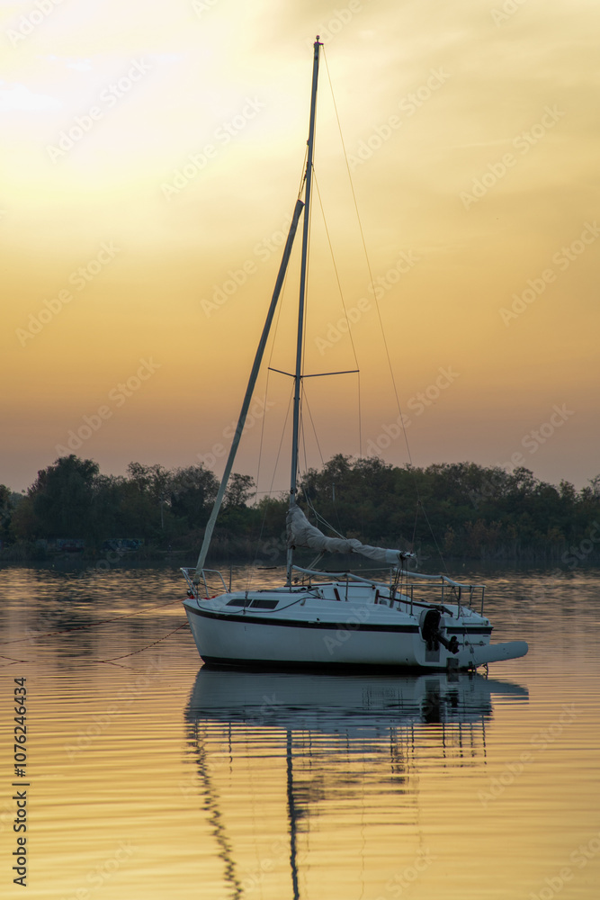 A serene sailboat floats on a calm lake at sunset, embodying relaxation and wanderlust during the summer vacation A serene sailboat floats on a calm lake at sunset, embodying relaxation and wanderlust during the summer vacation