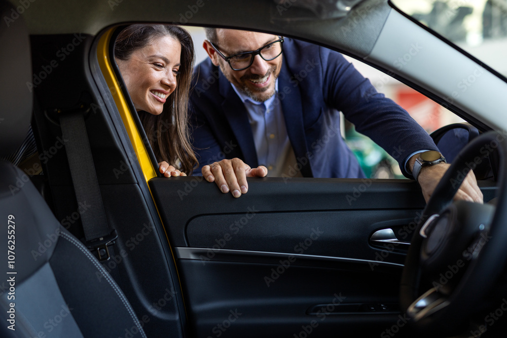 Cute couple sitting in a car at a dealer while deciding whether to buy. Spouses Looking At Car Interior Buying Vehicle In Store. We should organize a test drive Cute couple sitting in a car at a dealer while deciding whether to buy. Spouses Looking At Car Interior Buying Vehicle In Store. We should organize a test drive