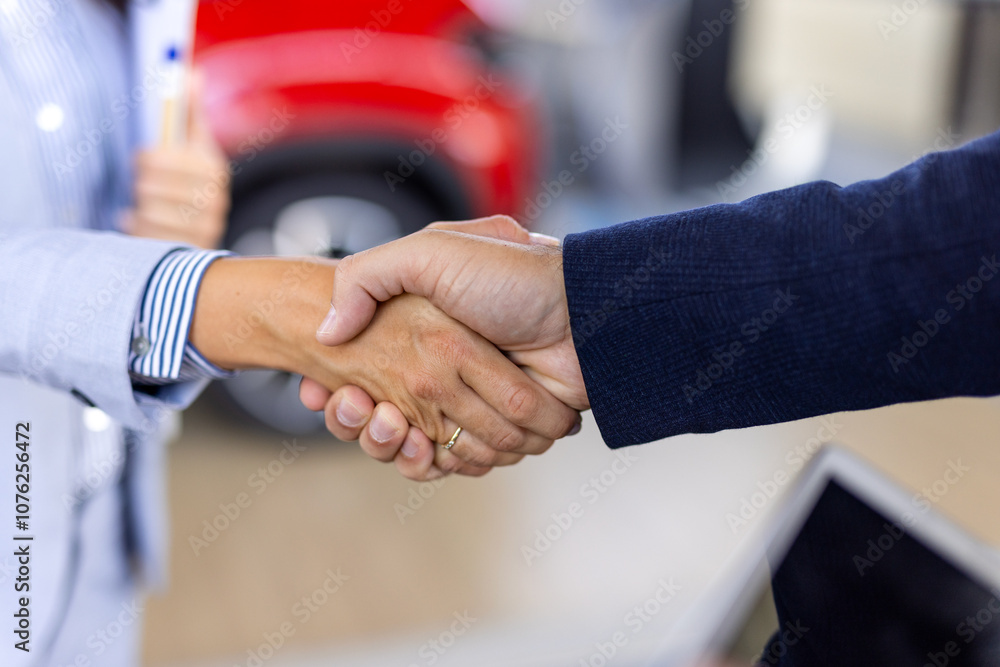 Smiling salesman or manager giving car keys and shakes hand to modern happy woman new car owner in car dealership Smiling salesman or manager giving car keys and shakes hand to modern happy woman new car owner in car dealership