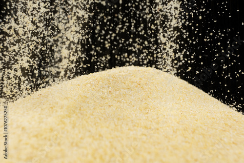 Tableau sur toile Uncooked dry semolina pour on a black background