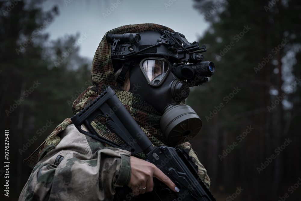 A girl soldier in a gas mask and a tactical helmet with a night vision monocular in the forest at dusk. A girl soldier in a gas mask and a tactical helmet with a night vision monocular in the forest at dusk.