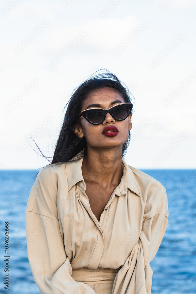 Young indian fashion model wearing sunglasses and posing by the sea Young indian fashion model wearing sunglasses and posing by the sea
