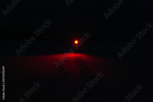 Obraz na płótnie A Person in the Snow Shining a Creepy Red Flashlight in the Dark Night w salonie