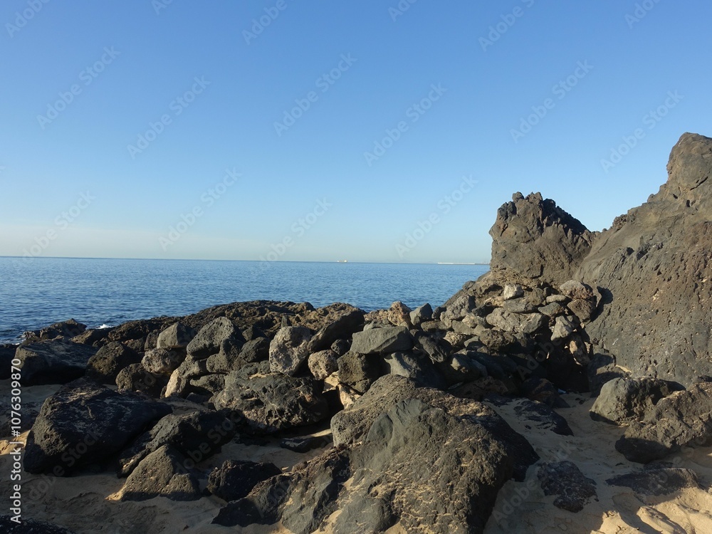 Rocky coastline with black volcanic rocks and calm ocean. Rocky coastline with black volcanic rocks and calm ocean.