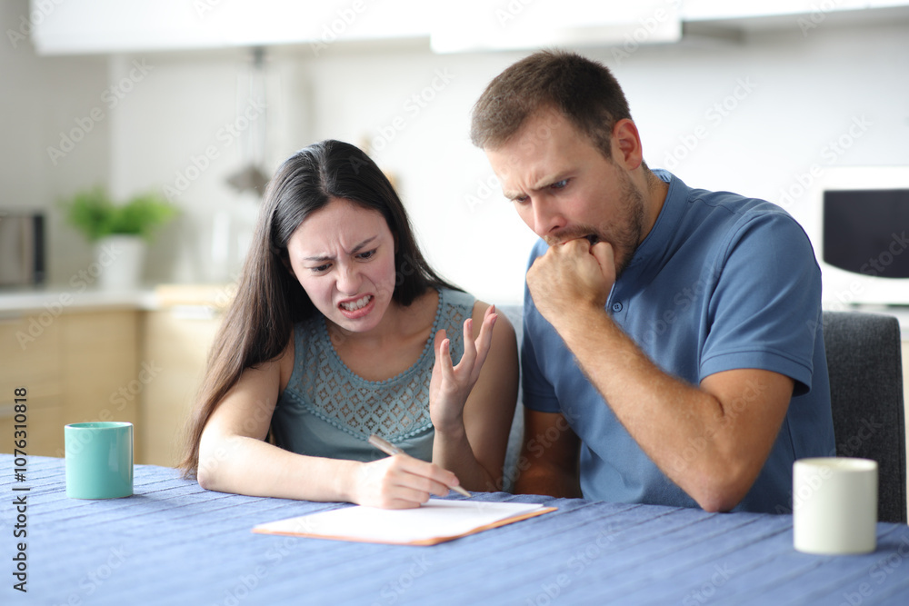 Angry couple checking contract in the kitchen Angry couple checking contract in the kitchen