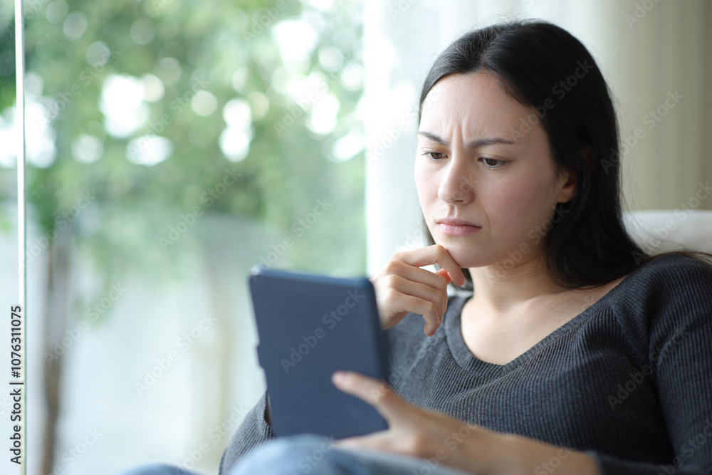 Confused asian woman reading ebook Confused asian woman reading ebook
