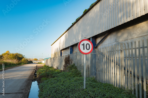 10 Mph speed limit sign seen on a British industrial estate. A sharp bend in the distance, used by HGVs means speeds need to be kept to a minimum. photo