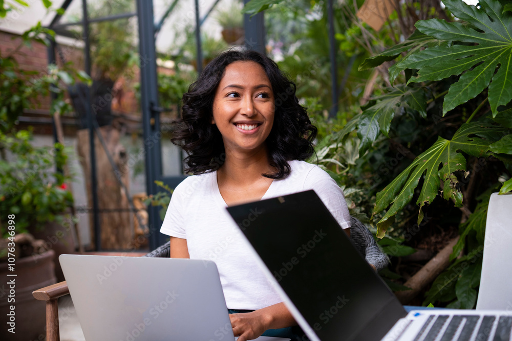 Smiling woman with laptop working in urban garden Smiling woman with laptop working in urban garden