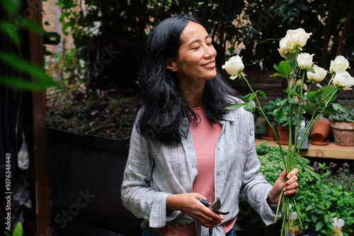 Happy gardener smelling white rose flower in garden center photo