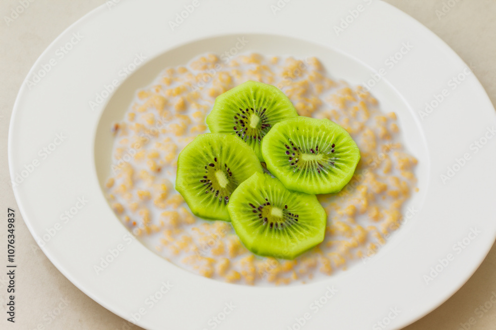Plate of porridge, kiwi, and white. meal food diet concept. a plate of porridge with kiwi and white cheese on a sunny morning. a plate of porridge with sliced kiwi and milk on a lifestyle white plate. Plate of porridge, kiwi, and white. meal food diet concept. a plate of porridge with kiwi and white cheese on a sunny morning. a plate of porridge with sliced kiwi and milk on a lifestyle white plate.