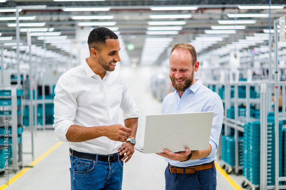 Two businessmen with laptop having a meeting in a factory Two businessmen with laptop having a meeting in a factory