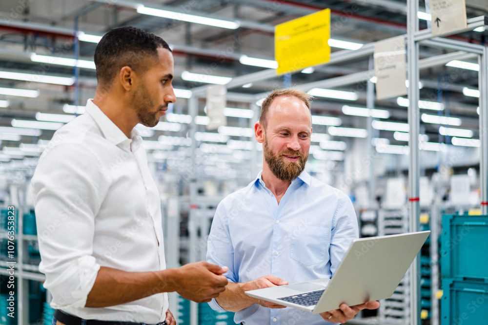 Two businessmen with laptop having a meeting in a factory Two businessmen with laptop having a meeting in a factory