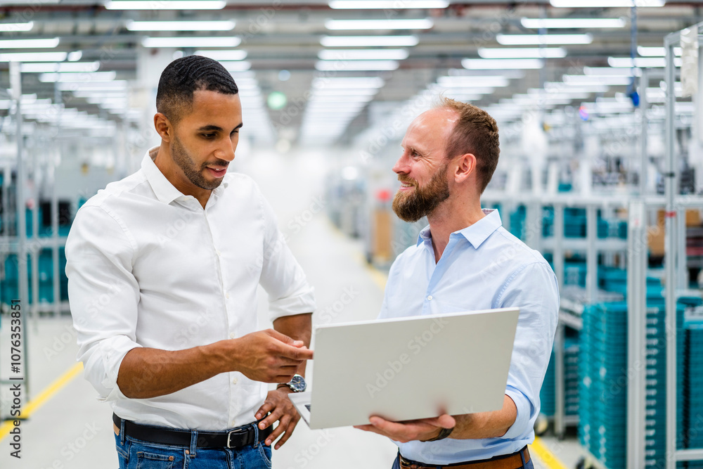 Two businessmen with laptop having a meeting in a factory Two businessmen with laptop having a meeting in a factory