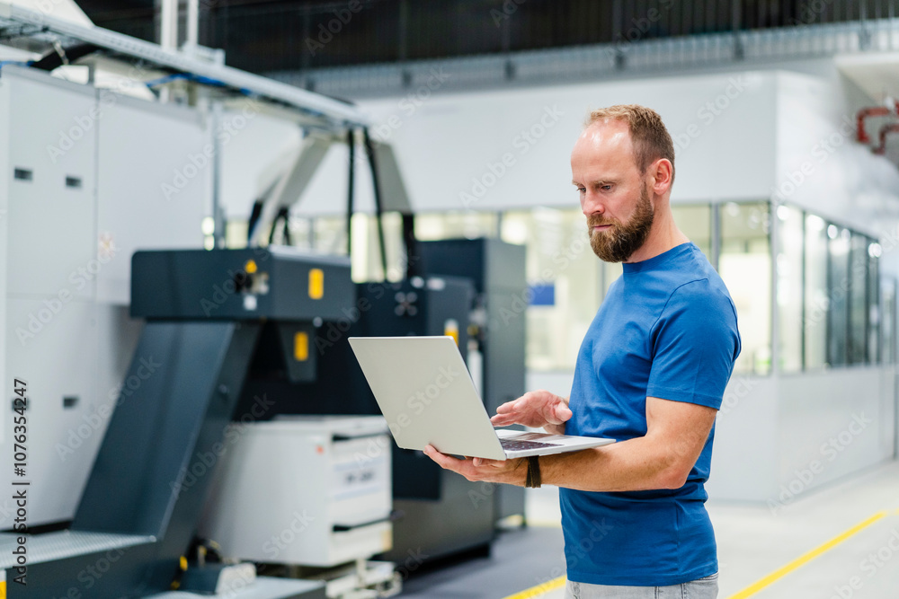 Technician using laptop on shop floor in a factory Technician using laptop on shop floor in a factory