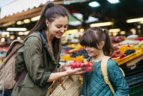 Mother and daughter shopping for fresh fruits and vegetables at the city market photo