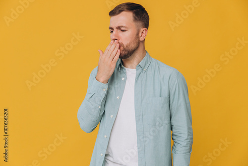 Unshaven man standing over yellow background feeling unwell and coughing as symptom for cold or bronchitis. Health care concept.