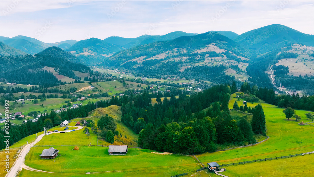 Scenic mountain village with green valleys. Aerial view of a picturesque mountain village surrounded by lush green fields, rolling hills, and dense forests, creating a serene landscape. Scenic mountain village with green valleys. Aerial view of a picturesque mountain village surrounded by lush green fields, rolling hills, and dense forests, creating a serene landscape.