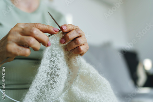 Hands of senior woman knitting shawl at home photo