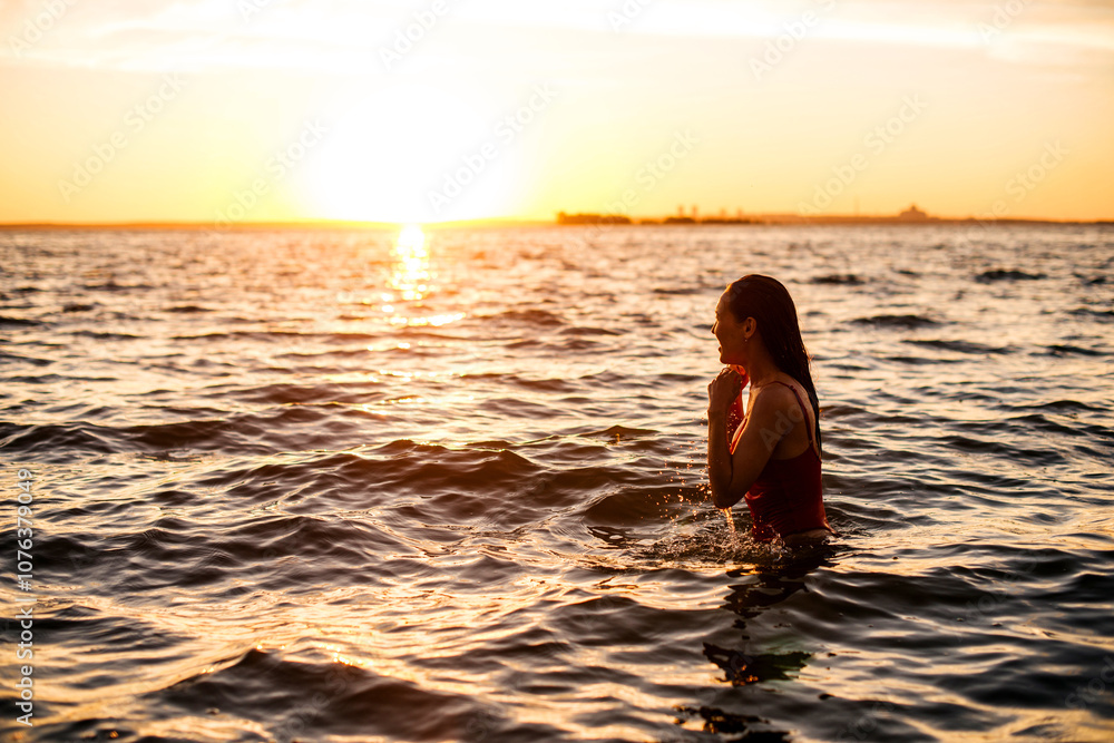 A girl in a red swimsuit on the beach at sunset A girl in a red swimsuit on the beach at sunset