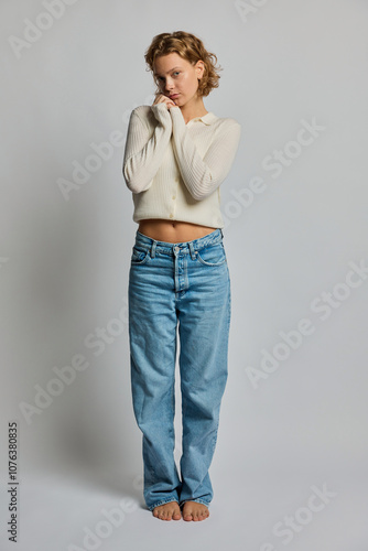 Innocent young woman hugging self against white background