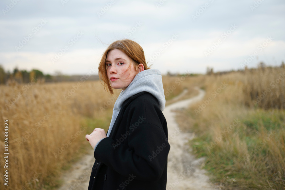 Redhead woman wearing hoodie and standing near field Redhead woman wearing hoodie and standing near field