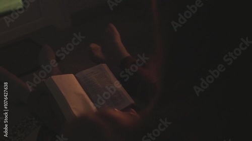 A mom with her son and daughter sitting on the floor next to the sofa and reading a book by the fireplace. Atmosphere of comfort and warmth in the house.