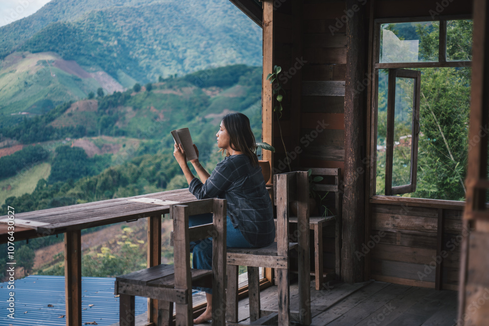 a woman sitting on a wood chair and reading a book in a mountain view a woman sitting on a wood chair and reading a book in a mountain view