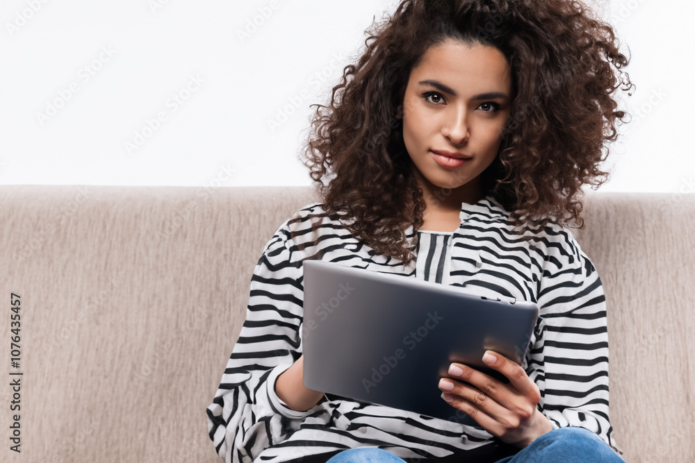 Girl is using tablet white . female person concept. young girl standing on sofa with her hands on tablet on a white . a young girl standing on a sofa with her hands up against a white lifestyle. Girl is using tablet white . female person concept. young girl standing on sofa with her hands on tablet on a white . a young girl standing on a sofa with her hands up against a white lifestyle.
