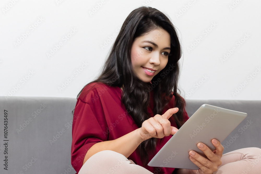 Girl is using tablet white . female person concept. young girl standing on sofa with her hands on tablet on a white . a young girl standing on a sofa with her hands up against a lifestyle white. Girl is using tablet white . female person concept. young girl standing on sofa with her hands on tablet on a white . a young girl standing on a sofa with her hands up against a lifestyle white.