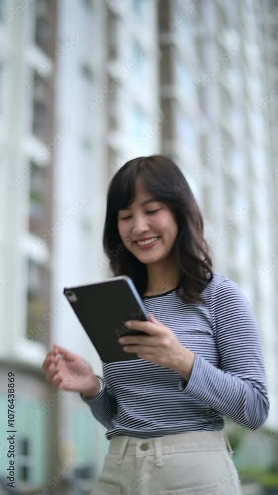 Vertical video of Woman Stands Outside Modern Urban Building Using Tablet with Focus and Concentration, Engaged in Technology in City Environment Vertical video of Woman Stands Outside Modern Urban Building Using Tablet with Focus and Concentration, Engaged in Technology in City Environment