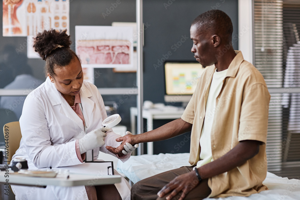 Fototapeta premium Side view medical scene with female dermatologist examining patient using magnifying glass in clinic