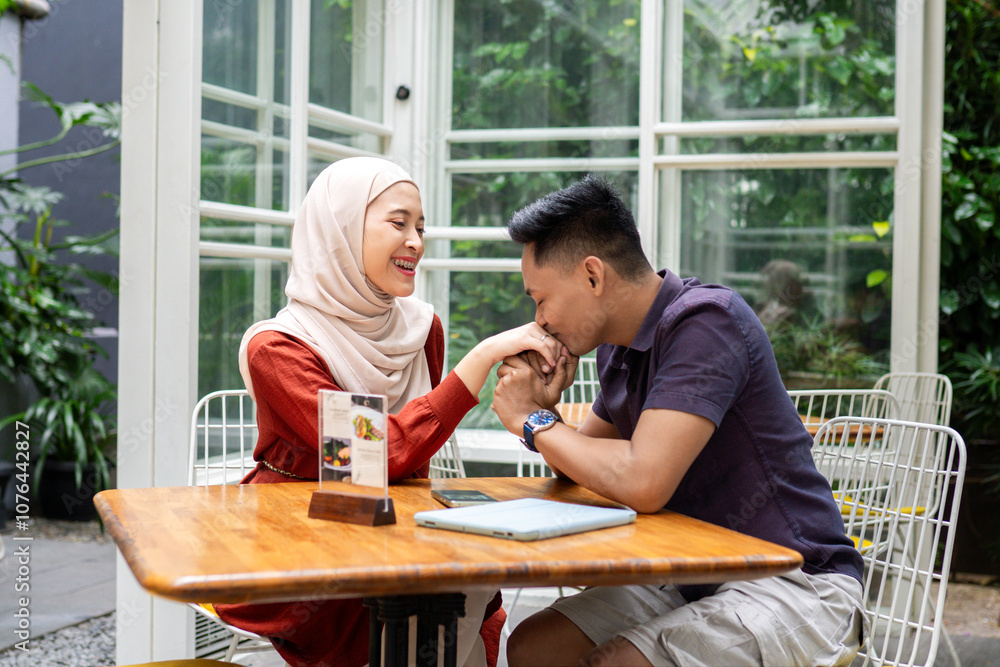 A joyful couple sharing laughter and bonding at an outdoor cafe table, surrounded by lush greenery and cozy atmosphere. Perfect representation of happiness and connection. A joyful couple sharing laughter and bonding at an outdoor cafe table, surrounded by lush greenery and cozy atmosphere. Perfect representation of happiness and connection.