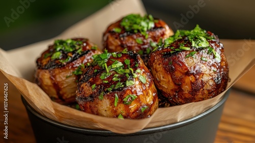 Four succulent grilled meatballs are drizzled with a glossy herb glaze in a paper-lined bowl, offering a mouthwatering display of culinary delight.