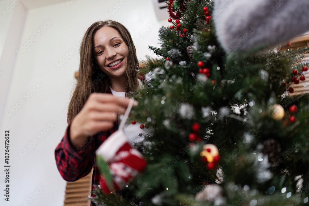 Smiling Woman Decorating Christmas Tree with Ornaments in Festive Holiday Setting at Home Smiling Woman Decorating Christmas Tree with Ornaments in Festive Holiday Setting at Home