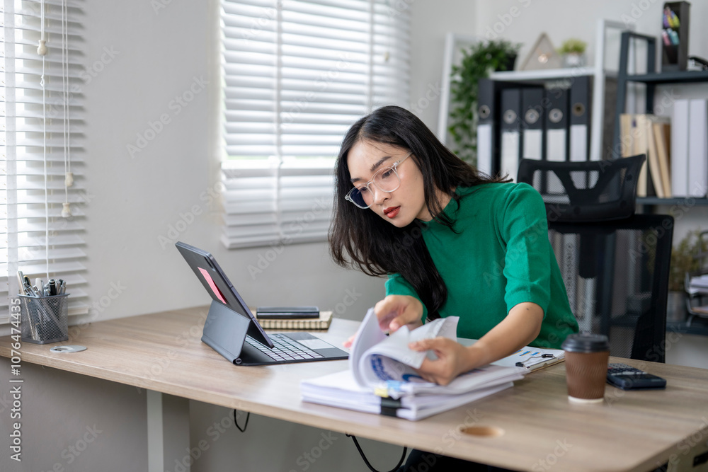 Young asian businesswoman working with documents and digital tablet at the office Young asian businesswoman working with documents and digital tablet at the office