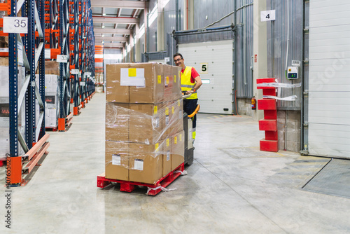 Foto Warehouse worker transporting goods on pallet jack in logistics center