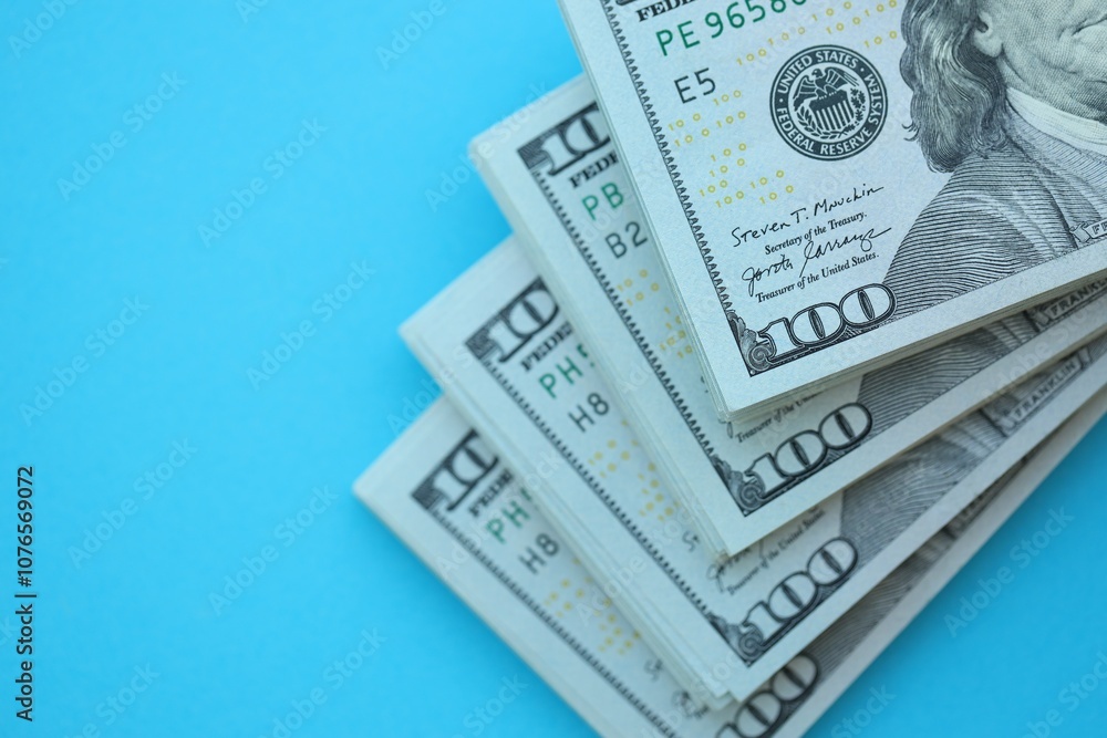 Big amount of hundred dollar bills in thick stack lies on bright blue color paper background Big amount of hundred dollar bills in thick stack lies on bright blue color paper background