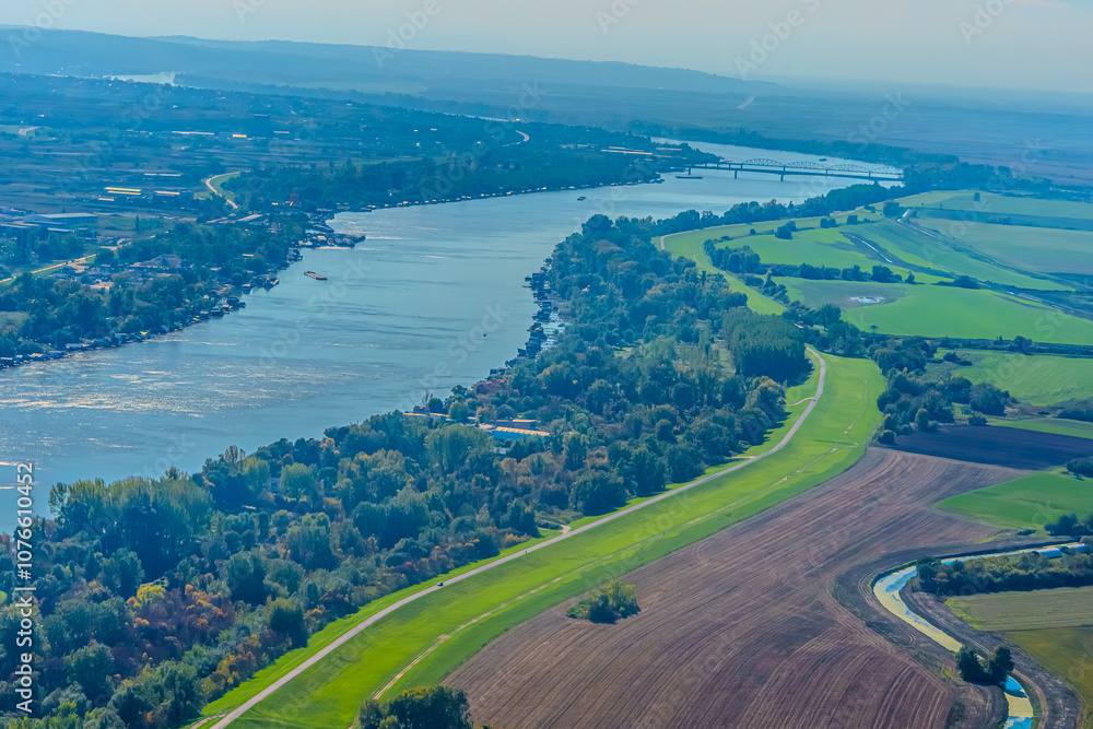 Fototapeta premium Aerial view of valley with farm fields, pond and Danube river. High quality photo
